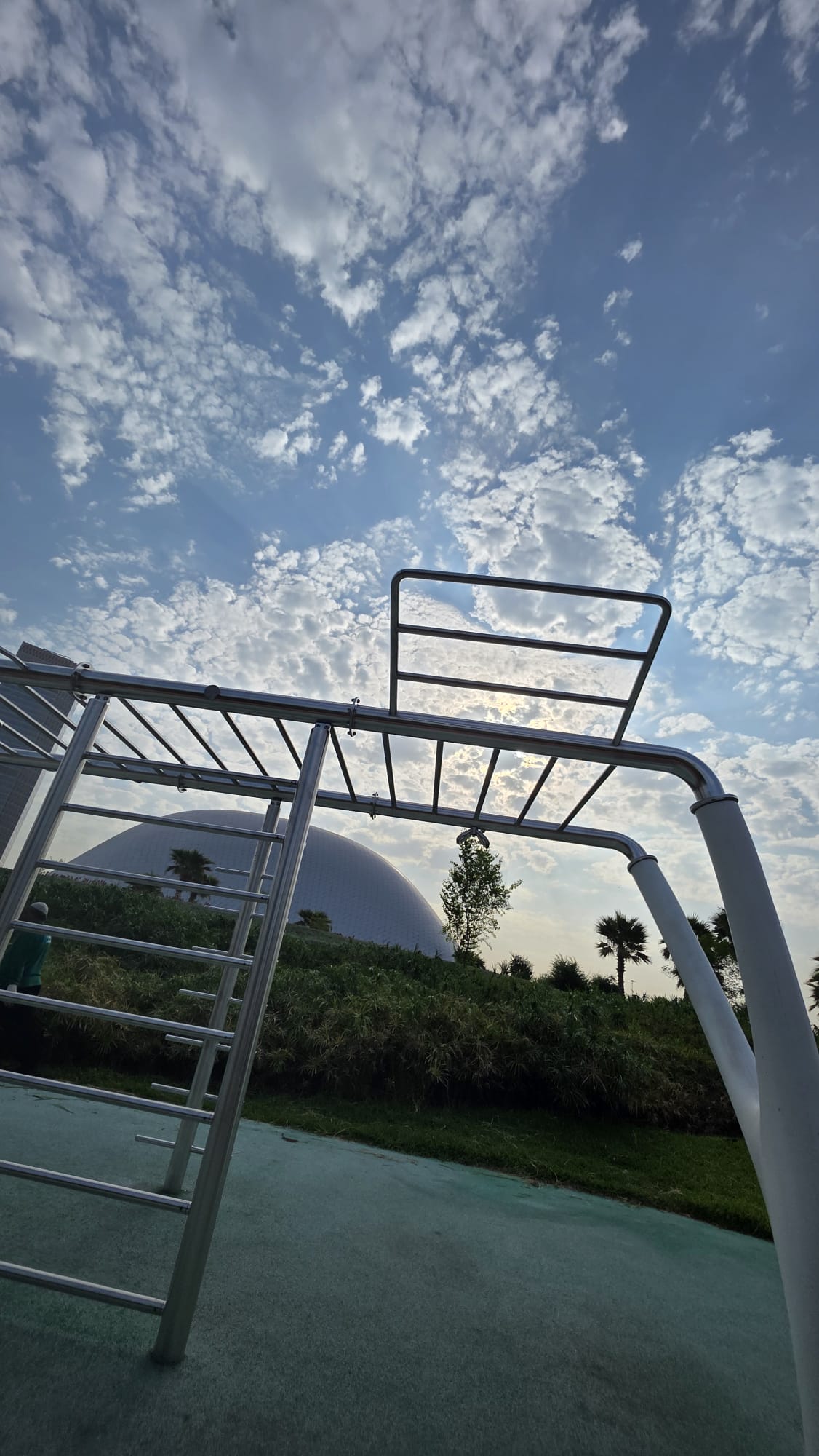 Silver exercise bars beneath a cloud-filled sky at the park